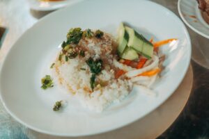 Mała porcja ryżu z warzywami na białym talerzu, symbolizująca skromne posiłki w szpitalu i ciche niedożywienie pacjentów przy jednym dietetyku na pół szpitala w polskiej ochronie zdrowia.